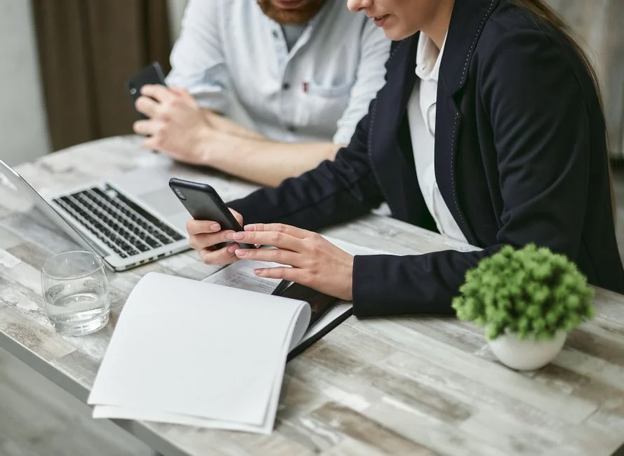 Un espace de travail moderne où l’on voit des mains analyser des données marketing sur un ordinateur portable et des documents papier.
